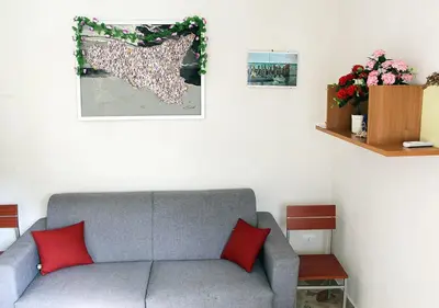 a living room with a gray couch and red pillows at Don Vito's Apartments in Castellammare del Golfo