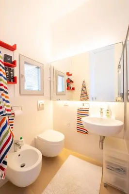 a white bathroom with a toilet and a sink at La Bougainvillea casa vacanze in Alcamo