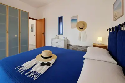 a bedroom with a blue bed with a hat and bow tie at Green House con piscina privata 7 posti in Macari