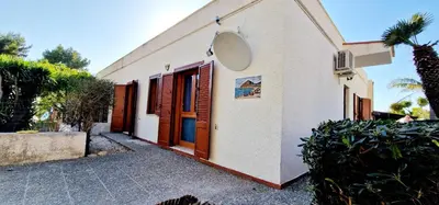 a white house with wooden doors and a courtyard at Green House con piscina privata 7 posti in Macari