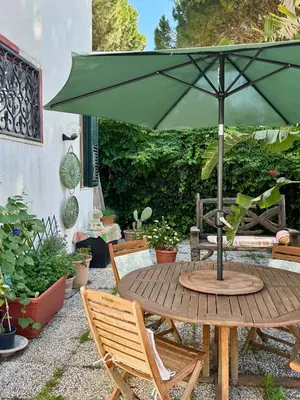 a table and chairs under a white umbrella at B&B Ondamarina in Lascari