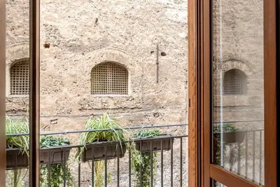 a window view of a stone building with plants on a balcony at Casa Dolce Vita by Wonderful Italy in Palermo