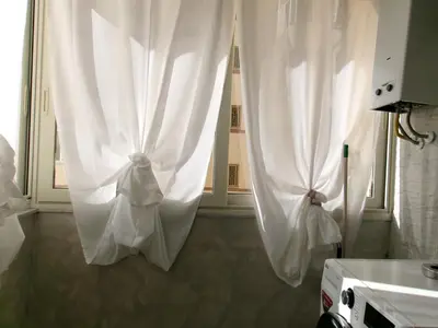 two white curtains are hanging in a kitchen at Antadia Terminal Bus in Palermo