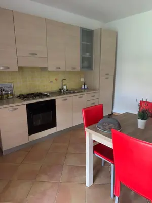 a kitchen with a wooden table and red chairs at Villetta giardino, piscina, mare in Campofelice di Roccella