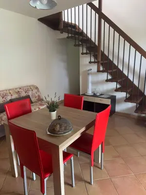 a dining room table with red chairs and a staircase at Villetta giardino, piscina, mare in Campofelice di Roccella