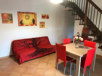a living room with a table and red chairs and a couch at Villetta giardino, piscina, mare in Campofelice di Roccella