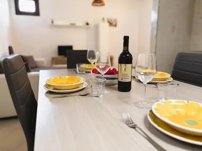 a table with a bottle of wine and glasses at Casa Amodei 1 a pochi passi dal mare in San Vito lo Capo