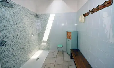 a bathroom with a shower with blue tiles and a stool at Villa Palme in Alcamo Marina