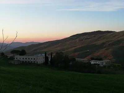 a building in a field next to a hill at Casale di Riena in Lercara Friddi