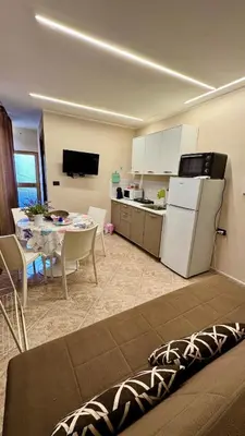 a room with a kitchen and a table with a refrigerator at FronteMare12 in Palermo