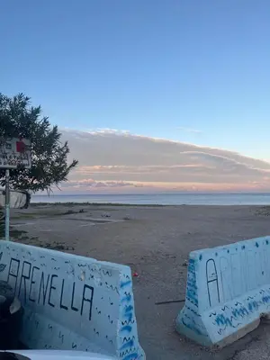 a sign on a beach with the ocean in the background at FronteMare12 in Palermo