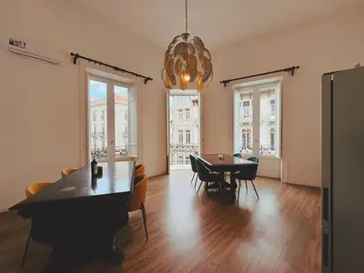 a dining room with a table and chairs and a chandelier at Candalù - Palermo Suite in Palermo