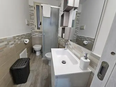 a white bathroom with a sink and a toilet at la casetta del baglio in Monreale