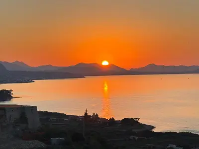 a sunset over a body of water with mountains in the background at Casa Ponticello in Termini Imerese