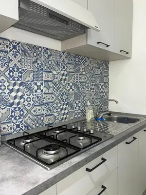 a kitchen with a stove and a tile wall at La Maiolica 61 in Terrasini