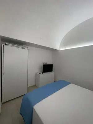 a white bedroom with a bed and a television at La Maiolica 61 in Terrasini