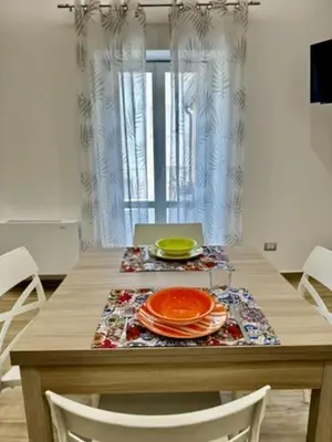 a bedroom with a white bed with four paintings on the wall at Terrasini Center Apartments in Terrasini