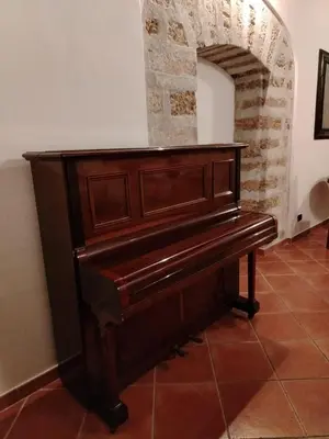 a wooden piano in a room with a brick wall at Vittorio Cathedral House in Palermo