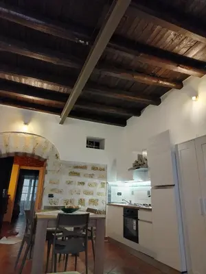 a kitchen with wooden ceilings and a table and chairs at Vittorio Cathedral House in Palermo