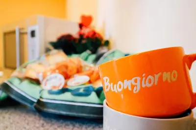an orange coffee cup sitting next to a plate of food at Kalsa Apartment in Palermo