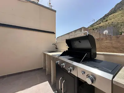 an outdoor kitchen with a grill on a roof at Gs Vacantion's del Golfo con vasca idromassaggio in Castellammare del Golfo