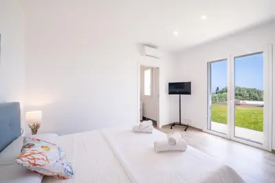 a white bedroom with a bed and a large window at Villa Manù country house in Castellammare del Golfo