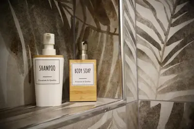 two bottles of soap sitting on a shelf in a mirror at Front Palermo House in Palermo