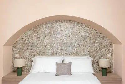 a bedroom with a white bed with a stone wall at Alabardieri Apartments by Wonderful Italy in Palermo