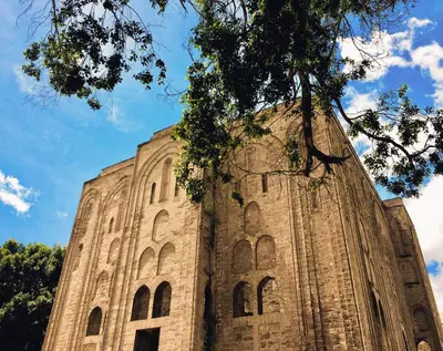 a large stone building with a tree in the foreground at Baglio dei Conti d'Orléans in Palermo