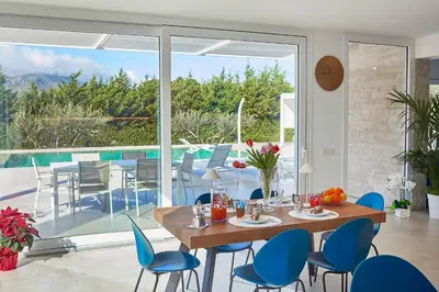 a dining room with a table and chairs and a pool at Villa the Twins in Castellammare del Golfo