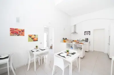 a white kitchen with white tables and chairs at Opera Suite in Castellammare del Golfo