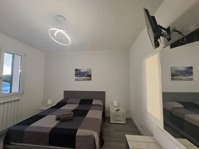 a bedroom with two beds and a television in it at Villa Elios Adriana con piscina a Lascari in Lascari