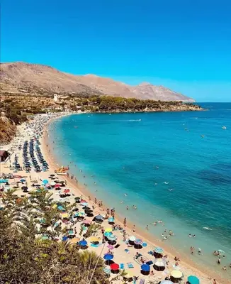 a beach with people and umbrellas and the ocean at Dimore Barraco - SiciliaDaMare in Castellammare del Golfo