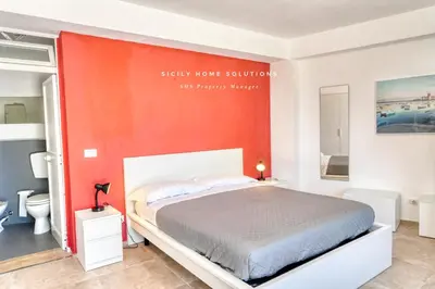 a bedroom with a bed and a red wall at Oasi Elegante Piscina di Lusso - vista panoramica By Sicily Home Solutions in Alcamo