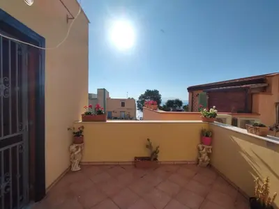 a balcony with potted plants and an open door at Casa Maria Elena in Santa Flavia