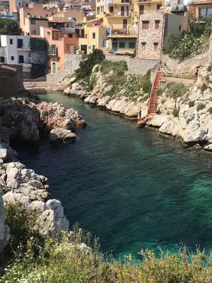 a river with rocks and buildings in a city at Casa Maria Elena in Santa Flavia