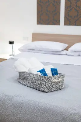 a basket of towels is sitting on a bed at 105 Apartments in Palermo