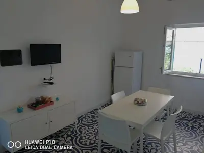 a white dining room with a white table and chairs at Capozafferano-Casa Carola in Santa Flavia
