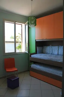 a bedroom with a bed and a chair and windows at Ville Tiffany in Campofelice di Roccella