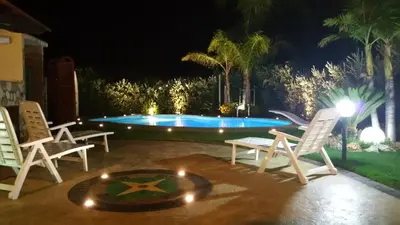 a patio with chairs and a pool at night at Ville Tiffany in Campofelice di Roccella