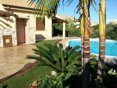 a house with a swimming pool and a palm tree at Ville Tiffany in Campofelice di Roccella