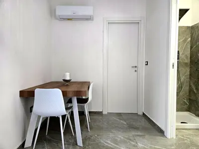 a dining room with a wooden table and white chairs at Vicoletto Natalia - Proppro SRL- Palermo in Palermo