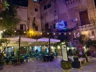 an outdoor restaurant with tables and umbrellas at night at Nova Holidays in Palermo