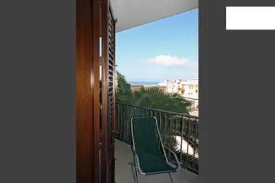 a green chair on a balcony with a view of the ocean at Pompei in Castellammare del Golfo
