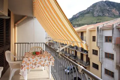 a balcony with a table and chairs and an umbrella at Pompei in Castellammare del Golfo