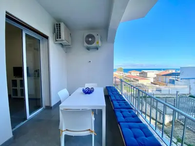 a white table and chairs on a balcony with a view at Casa La Mamà, a 150 mt dal mare in Alcamo