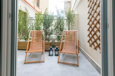 two wooden chairs sitting on a patio with a window at With love, Apartment 4 in Palermo