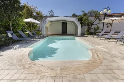 a swimming pool with chairs and an umbrella at Villa Sandoval in Palermo
