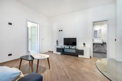 a white living room with a tv and a couch at Villa Sandoval in Palermo
