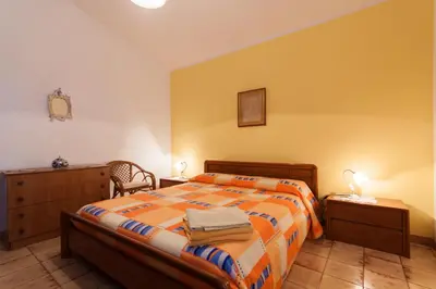 a bedroom with a bed and a table and a chair at Villino Dei Gabbiani in Castellammare del Golfo